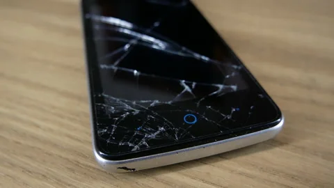 A mobile phone with a broken screen lies on a table 스톡 동영상 130243455