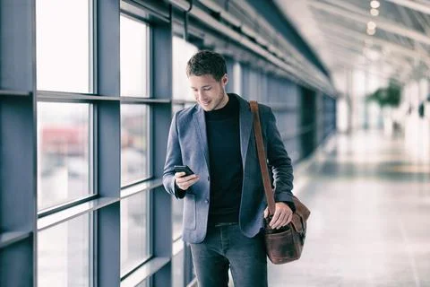 Mobile phone business man walking in airport with messenger bag using cellphone Stock Photos