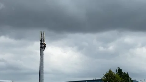 Mobile phone engineer working up a telecom mast using harness to climb Stock Footage 280747364