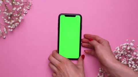 Mobile phone with green screen in hand on pink background, using technology Video stock 132396086