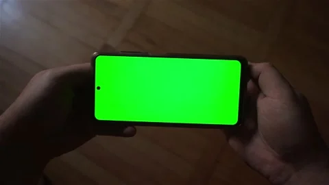 A mobile phone with a green screen is held in the hands Stock Footage 164035888