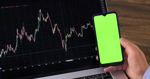 A mobile phone with a green screen next to the laptop screen Stock-Footage 218468236