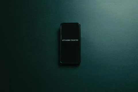 Mobile phone over a dark background with a motivational message written in .. Foto stock