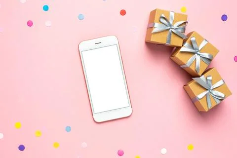 Mobile phone, present boxes and color confetti on pink table. Composition f.. Stock Illustration