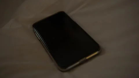 Mobile Phone Resting on Bed in Soft Indoor Light, Close-Up Technology Scene Stock Footage 345681667