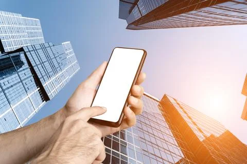 Mobile Phone Screen Mockup Held in Hand Against Towering Downtown Skyscrapers Stock Photos