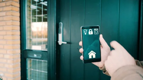 Mobile phone shows app to lock and unlock front door in smart home Stock Footage 102160179