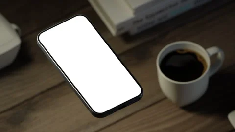The mobile phone is slightly raised above the wooden table, showing the e-scr Stock Footage 261365539