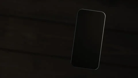 The mobile phone is slightly raised above the wooden table, showing the scree Stock Footage 261365872