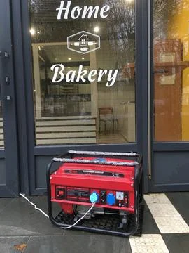 Mobile power generator at the door of the bakery during the blackout. Foto stock