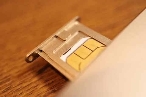 Mobile SIM card placed in a metal tray ejector on a wooden table surface fo.. Stock Photos