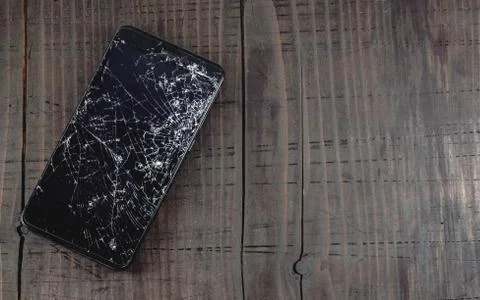 Mobile smartphone with broken touch screen on old wooden table, top view. Фото