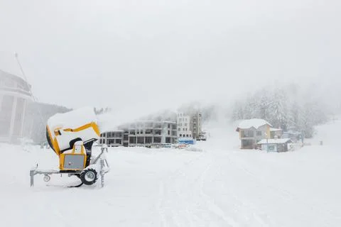 A mobile snow making machine on ski slope pumps out snow. Stock Photos
