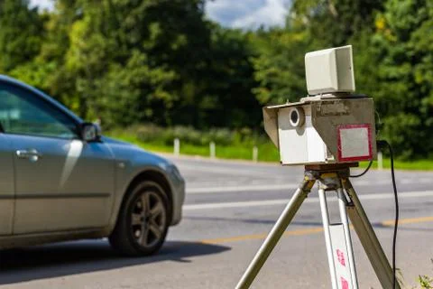 Mobile speed camera device working on summer daytime road with blurry silver car Stock Photos