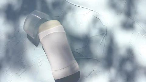 Mock up a bottle of deodorant with shadows of leaves on blue background Stock Footage 128961830