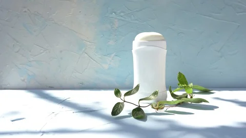 Mock up a bottle of deodorant with shadows of leaves on blue background Stock Footage 128962074