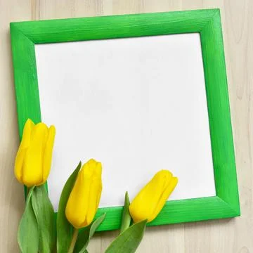 Mock up of bright green frame and three yellow tulips on wooden background Stock Photos