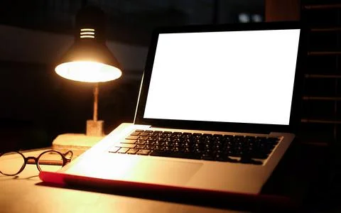 Mock up computer laptop with empty display and glowing lamp on wooden table i Stock Photos