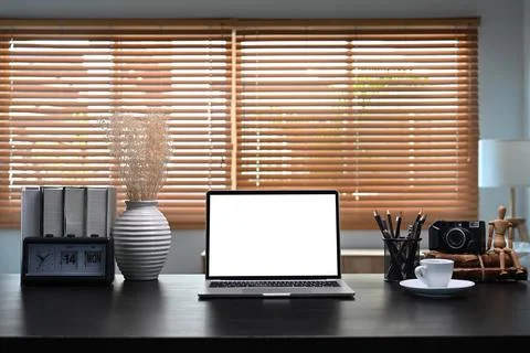 Mock up computer laptop with white screen on black tale in home office. Stock Photos