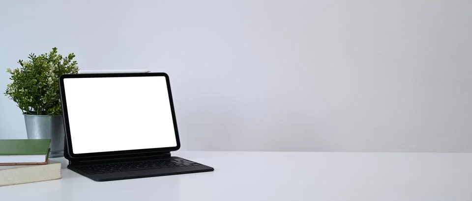 Mock up computer tablet with blank screen, house plant and books on white tab Foto stock