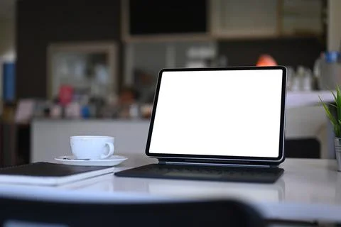 Mock up computer tablet with empty screen, notebook and coffee cup on white t Stock Photos
