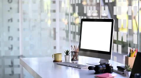 Mock up computer with white screen, camera and office supplies on photographe Stock Photos