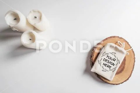 Mock up of cotton bag or pouch on wooden cut tree section and white candles PSD-Vorlage