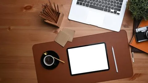 Mock up digital tablet with white display and laptop computer on wooden table. Stock Photos