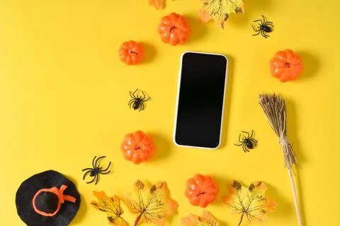 A mock-up of an empty Halloween phone with pumpkins and spiders on a yellow b Stock Photos