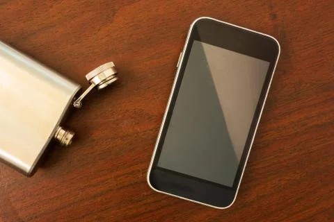 Mock up flat lay of blank smartphone screen and open empty flask on the table 库存照片