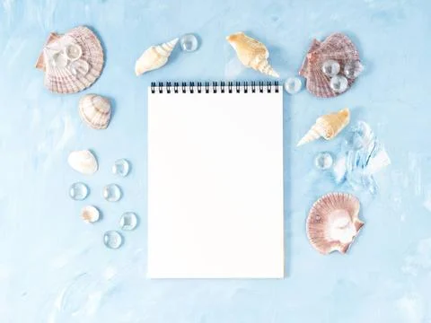 Mock up with frame of seashell, notepad on blue stone backdrop, copy space... Stock Photos