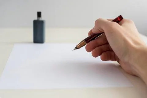 Mock up image on hand with rapidograph writes, draws on white leaf of paper Stock Photos