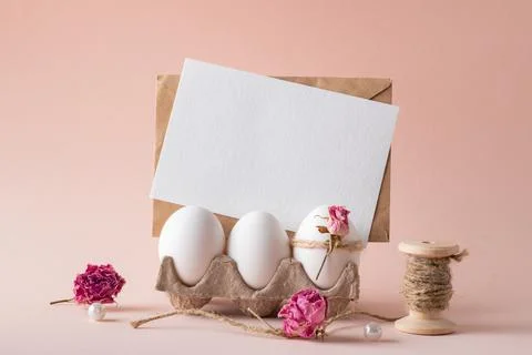 A mock-up of an invitation with Easter eggs and an eco-decor of dried roses and Stock Photos