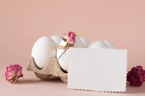 A mock-up of an invitation with Easter eggs and an eco-decor of dried roses and Stock Photos