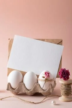 A mock-up of an invitation with Easter eggs and an eco-decor of dried roses and Stock Photos
