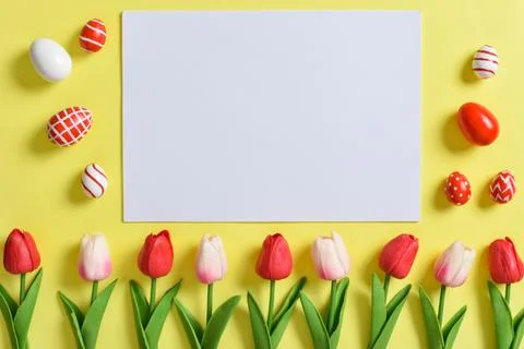 A mock-up of an invitation with tulips and Easter eggs. Stock Photos