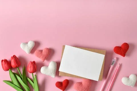 A mock-up of a kraft envelope with a blank sheet, tulips and knitted hearts. Stock Photos