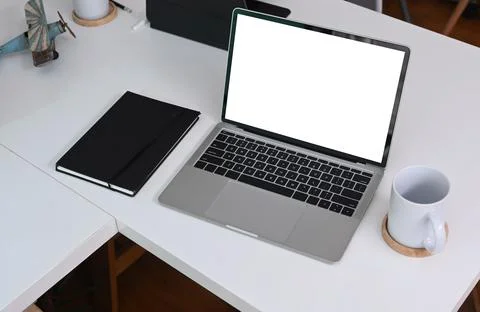 Mock up laptop computer with blank screen, notebook and coffee cup on white o Stock Photos