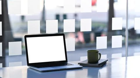 Mock up laptop computer with blank white screen and coffee cup on simple work Stock Photos