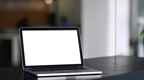 Mock up laptop computer with blank white screen on black wooden table at mode Stock Photos