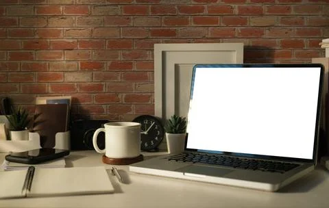 Mock up laptop computer, coffee cup and suppliers on white table. Empty scr.. Stock Photos