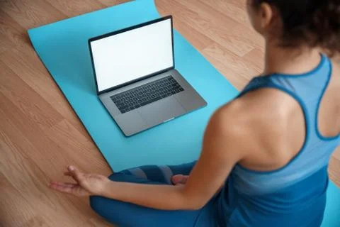 Mock up on laptop computer in front of young fit sporty woman training yoga. Stock Photos