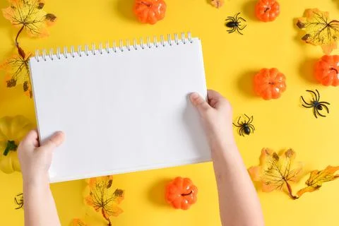 A mock-up of a notebook in children's hands for Halloween with pumpkins and s Stock Photos