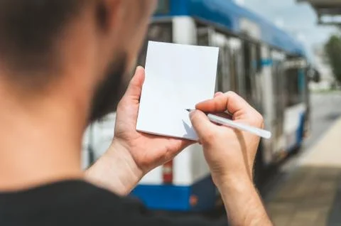 Mock Up notebook in a man's hand, against the background of public transport. Stock Photos