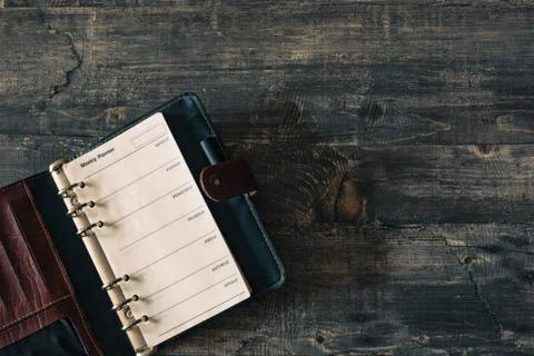 Mock-up Old notebook weekly planner on dark wooden table desk. Flat lay templat. Stock Photos