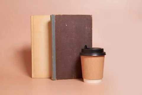 Mock up. A paper cup of coffee stands next to a stack of old books Stock Photos