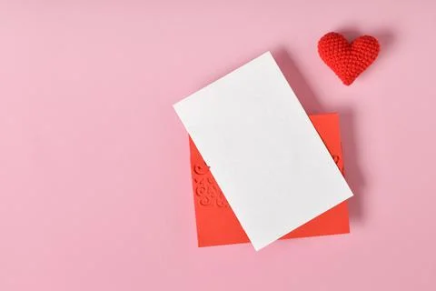 A mock-up of a red envelope with a blank sheet and a red knitted heart on a p Foto stock