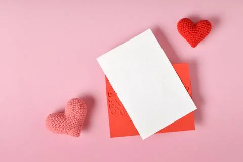 A mock-up of a red envelope with a blank sheet and two knitted hearts on a pi Stock Photos