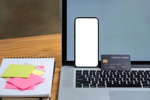 Mock up smartphone device with blank screen standing on laptop computer with Stock Photos