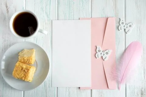 Mock up template with envelope, cup of tea, cake and pink feather. View from Stock Photos